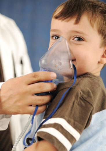 Criança fazendo inalação com máscara segurada por médico.
